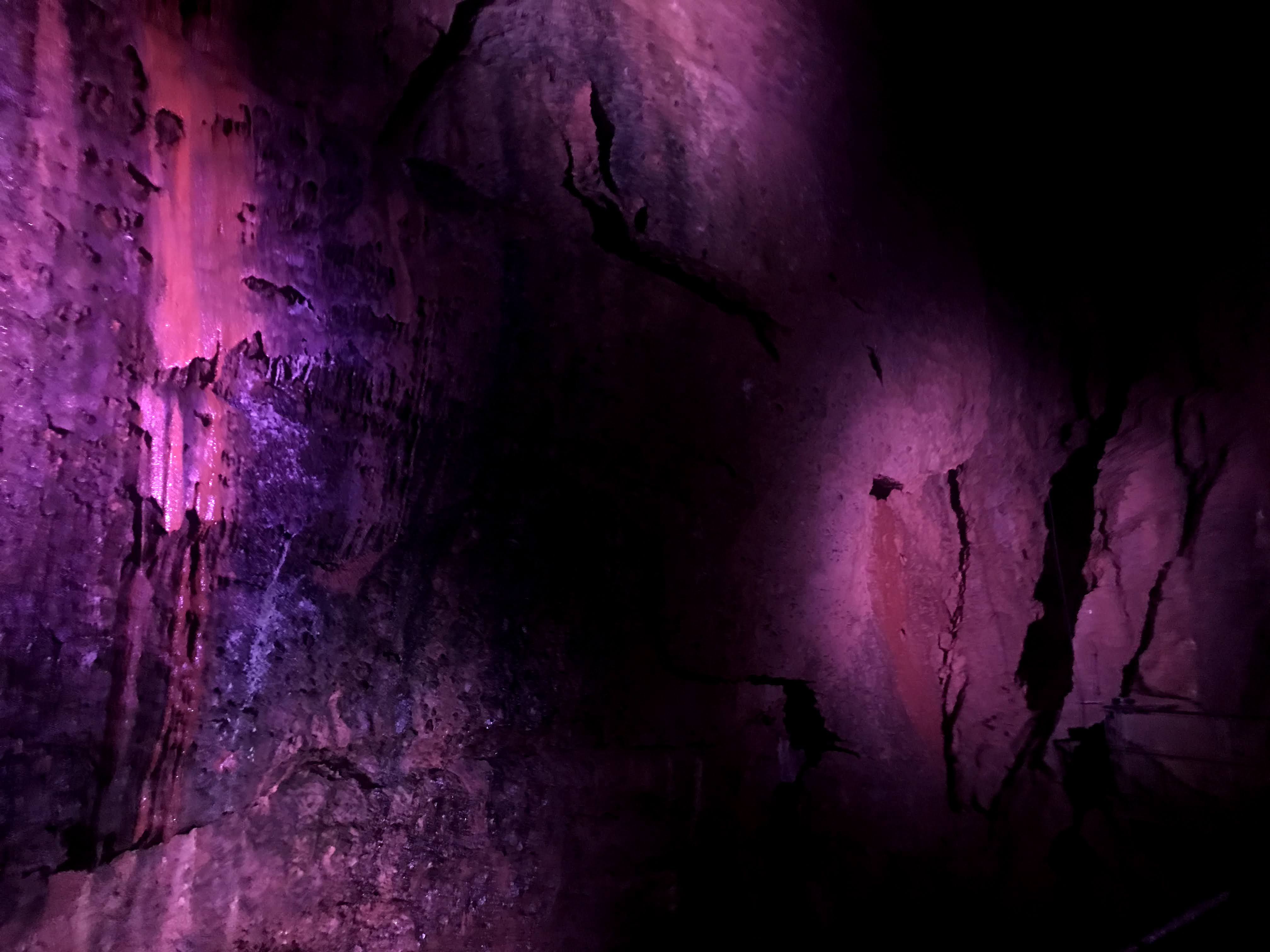 A cave wall, with a lit by a purple light.